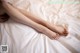 A woman laying on top of a bed with her legs crossed.