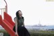 A woman sitting on a red slide looking up at the sky.