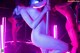 A naked woman is standing on a pole in a nightclub.