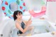 A woman sitting in a bathtub with two inflatable watermelon rings.