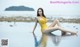 A woman in a yellow bathing suit sitting in the water.