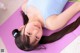 A woman laying on a purple yoga mat with her eyes closed.