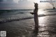 A woman in a white dress and hat standing in the ocean.