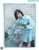 A woman holding a bunch of flowers in front of a brick wall.